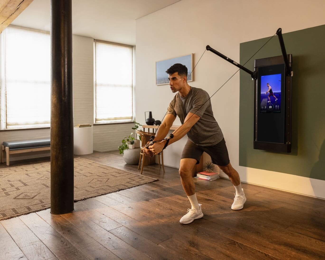 A man is working out in his living room. He is facing away from Tonal, completing a Decline Fly.