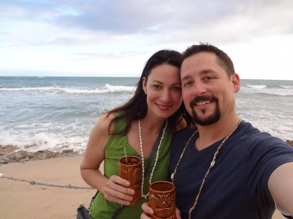 a man and woman on the beach drinking cocktails