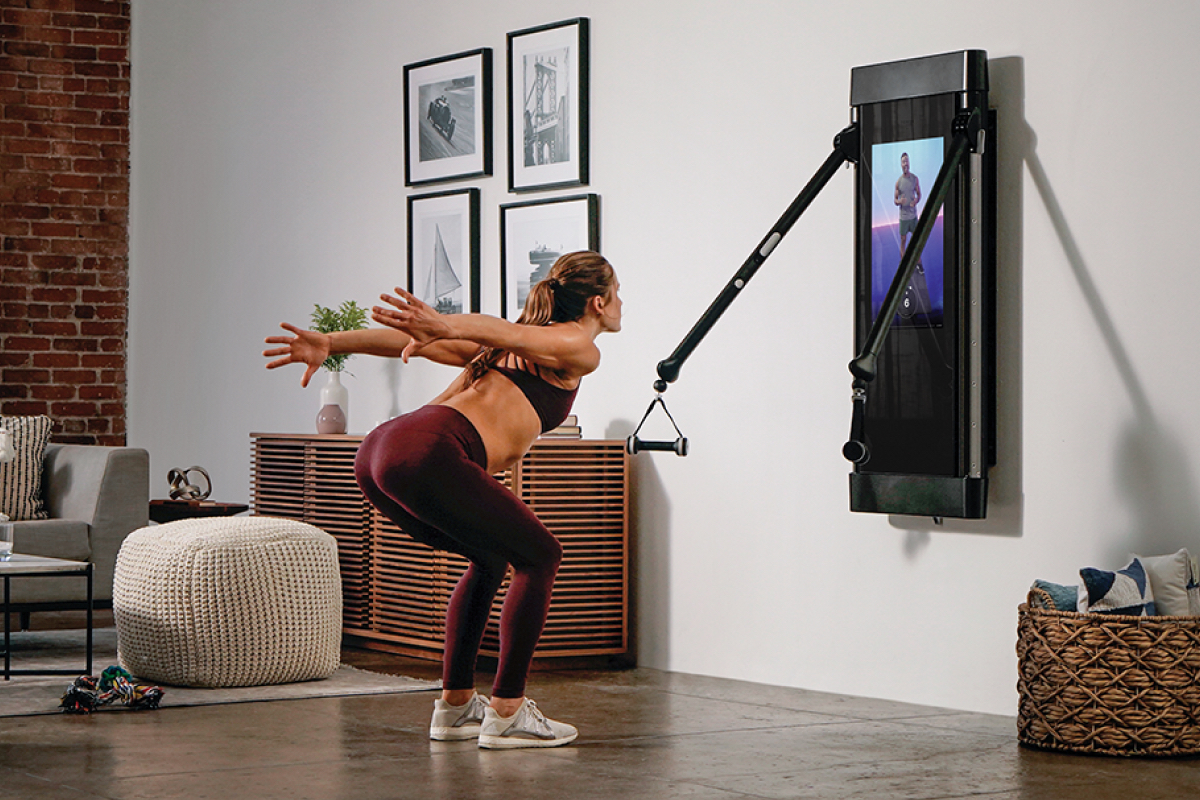 A woman performing calisthenics in a home setting in front of Tonal