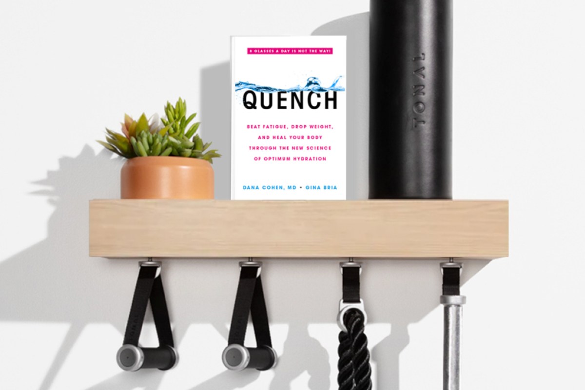 quench book cover on a shelf next to a tonal foam roller and plant with weight lifting accessories hanging off it