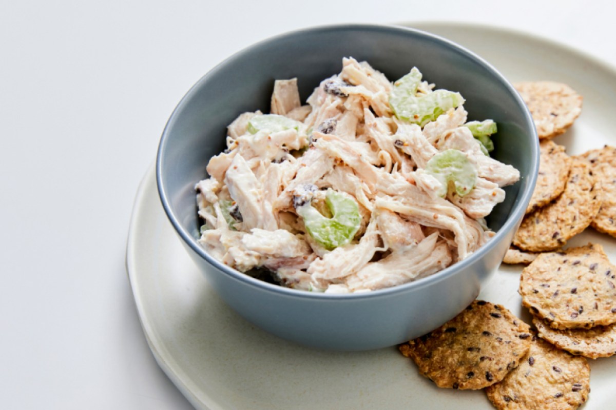 a bowl of chicken salad with crackers next to it