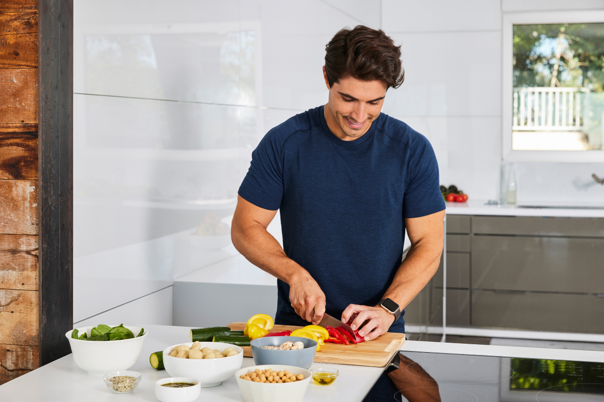 image of a man cutting up bell peppers while smiling in the kitchen demonstrating easy meal prep lunches