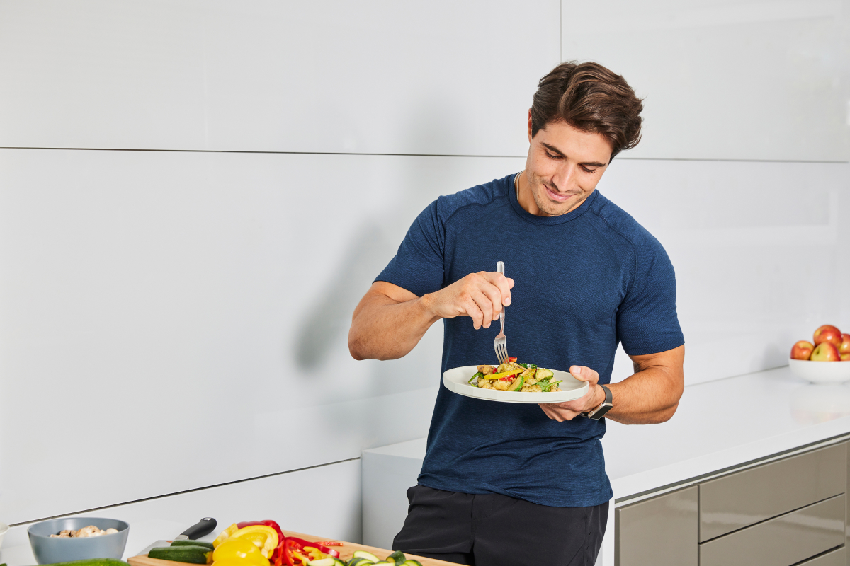 image of a man eating gnocchi in the kitchen demonstrating a healthy vegetarian dinner recipe