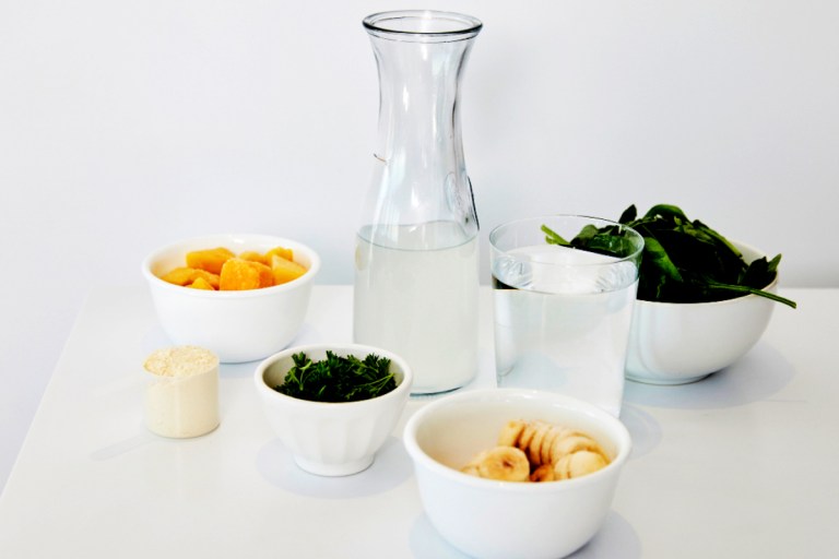 Image of healthy ingredients laid out with a glass bottle of water to highlight a focus on hydration.