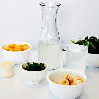 Image of healthy ingredients laid out with a glass bottle of water to highlight a focus on hydration.