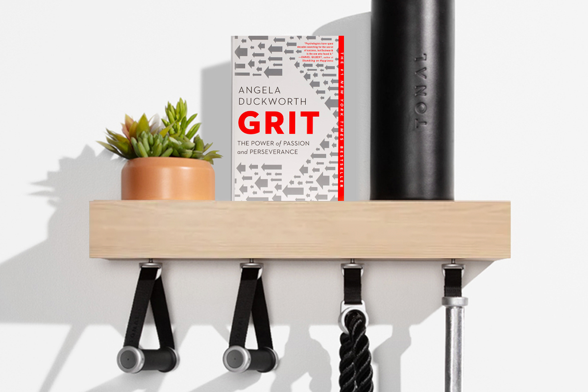 An image of the book "Grit" by Angela Duckworth sitting on a Tonal shelf illustrating that "Grit" is the April's Tonal book club pick.
